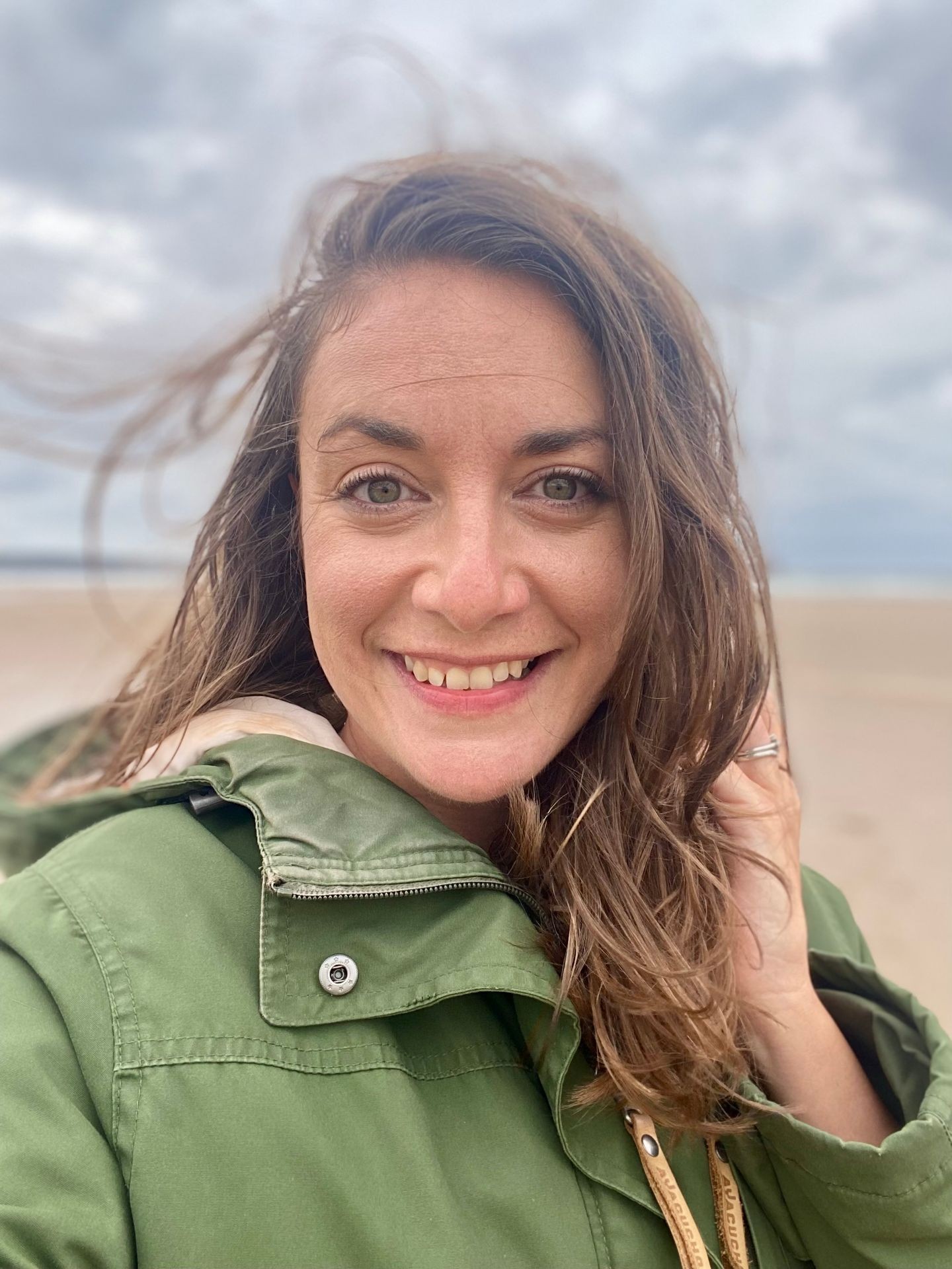 woman stands windswept on a beach